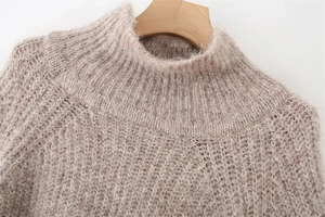 Close-up of the ribbed turtleneck and soft mohair texture of the beige knit sweater