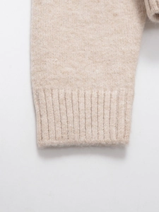 Macro view of ribbed knit cuff on beige sweater showing soft fabric texture and weave