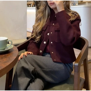Détail de la veste courte bordeaux avec tissu texturé et boutons en métal doré brillant