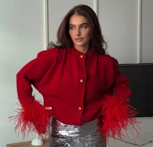 Detail of red knit cardigan with faux feather cuffs and gold embossed buttons