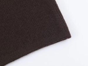 Detail of dark brown knit texture and ribbed cuff on a luxury wool blend sweater