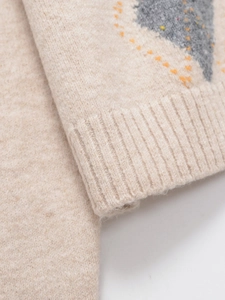 Close-up of beige argyle knit sweater with orange and grey patterns and ribbed cuffs