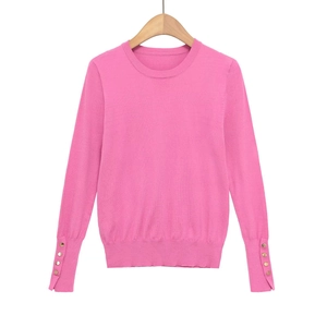 Detail of rose pink knit sweater showing golden decorative buttons on the sleeve cuffs