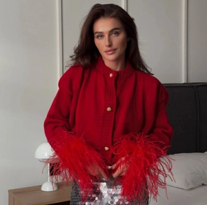 Detail of red knit cardigan with fluffy faux feather cuffs and gold embossed buttons