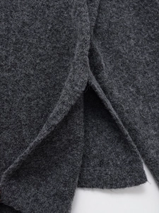 Gros plan détaillé sur la texture du mélange de laine gris foncé avec fente à l'ourlet