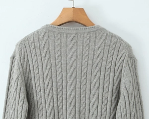 Detail of light grey cable knit sweater showing thick braided texture and crew neck