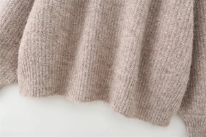 Close-up of the ribbed hem and soft knit texture on a brown grey oversized sweater