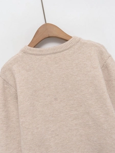 Detail view of oatmeal knit sweater showing premium wool blend texture on wood hanger