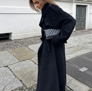 Detail view of black oversized wool coat with large lapels and double breasted closure