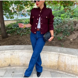 Détail d'une veste courte rouge style militaire avec boutons dorés et poches à rabat