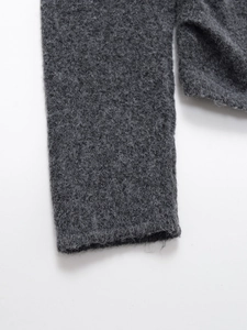 Détail de la texture en maille gris foncé et poignet sans couture d'un pull à manches longues