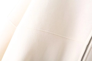 Close-up detail of high-density cotton fabric and silver metal zipper on white jacket