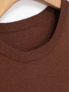 Detail of the ribbed crew neck on a high-quality dark brown knit sweater with a wood hanger