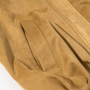 Detailed close-up of brown suede jacket showing neat welt pocket and double-stitch seams
