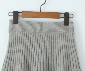 Detailed view of grey pleated knit skirt with vertical ribbing and elastic waistband