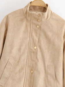 Detail of faux suede jacket featuring golden metal buttons and stand-up collar design