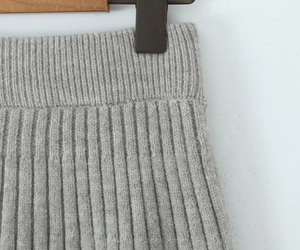 Detailed view of light gray rib-knit fabric texture on a wooden hanger with clip