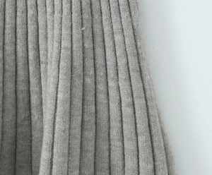 Close-up of grey cable knit fabric texture showing vertical ribbed details and soft fibers