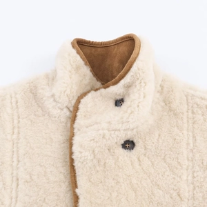 Detail of high collar cream faux shearling jacket with brown suede trim and black button