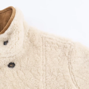 Detailed close-up of cream fleece jacket featuring brown suede piping and dark buttons