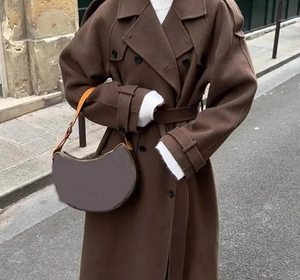 Detail of a brown wool trench coat with shoulder straps, lapels and a classic double-breasted design