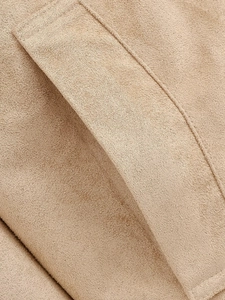 Macro shot of precise stitching and premium suede texture on a camel-colored jacket