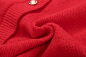 Detail of red knit cardigan showing fine texture and a silver decorative metal button