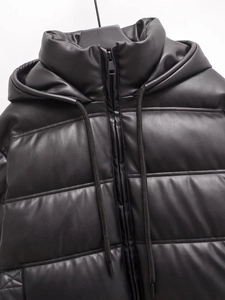 Dettaglio della trama in pelle PU e della cerniera metallica sul cappotto nero con cappuccio
