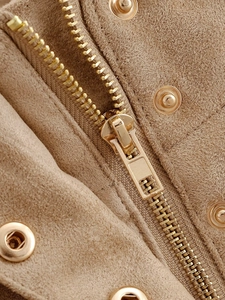 Detail of golden metal zipper and snap buttons on a light brown suede jacket fabric