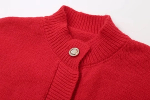 Detail of red knitted cardigan featuring a vintage gold button and ribbed collar
