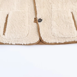 Close-up of sherpa wool jacket hem with brown suede piping and black button detail