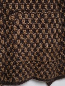 Macro shot of brown and yellow knitted fabric with geometric jacquard patterns