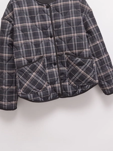 Macro detail of diamond-quilted grey plaid fabric with black buttons and piping