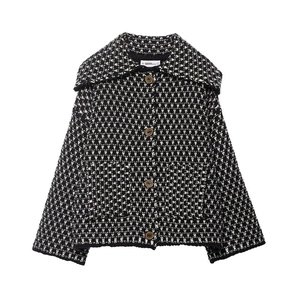 Detail of black and white patterned knit jacket with brown buttons and front pockets