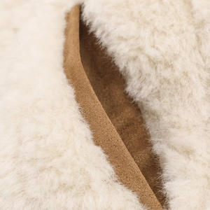 Close-up of fluffy cream faux fur texture with brown suede trim on the jacket