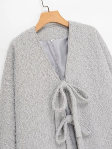Close-up of light grey plush coat with V-neckline, ribbon ties, and soft faux fur texture