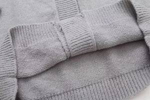 Detailed view of grey knit cardigan featuring high-quality ribbed hem and fine stitching