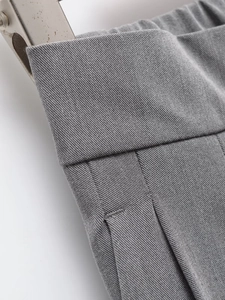 Macro detail of high-waist grey suit trousers with elastic waistband and twill texture