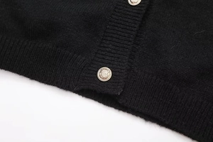 Close-up of black knit cardigan featuring vintage gold crest buttons and ribbed texture