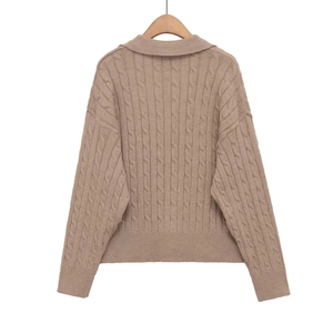 Macro detail of the classic cable-knit texture and soft fabric on the khaki sweater
