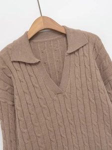 Close-up detail of warm khaki cable-knit texture and classic collar on long sleeve sweater