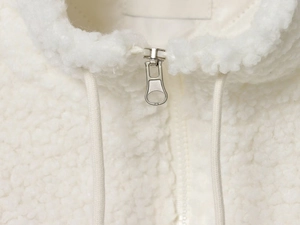 Detail of silver metal zipper and white drawstring on thick fleece baseball jacket