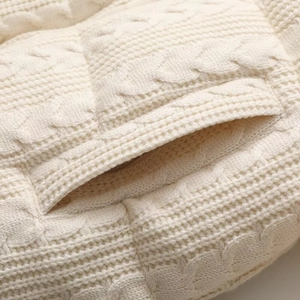 Macro shot of cream white cable knit texture and detailed horizontal side pocket on a jacket