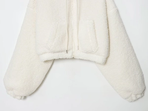Detail of white fleece jacket featuring soft sherpa texture and front zip closure