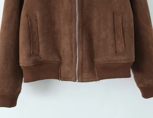 Détail de veste aviateur en daim marron avec fermeture éclair argentée et bord côtelé
