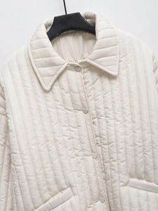 Detail of cream quilted jacket featuring unique silver heart-shaped buttons and lapels