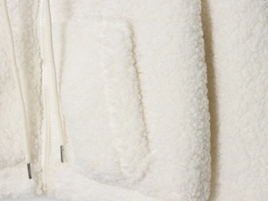 Detail of white fleece jacket with metal-tipped drawstring, smooth zipper and soft texture
