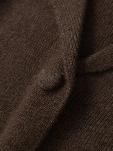 Dettaglio della trama della maglia e del bottone rivestito in tessuto di un cardigan marrone