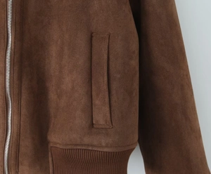 Détail de la texture suédine marron foncé avec fermeture éclair métallique et poche latérale