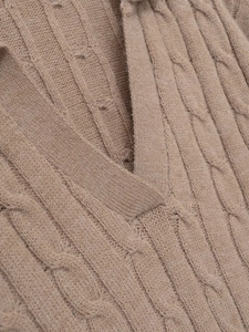Detail shot of beige cable-knit sweater featuring a classic V-neckline and thick texture